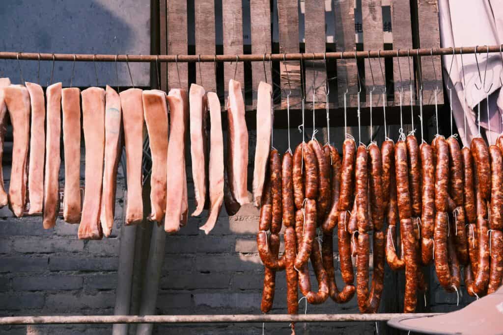 熟食腸粉和烤香腸掛在戶外晾曬，展現多元國際外勞集團特色。.