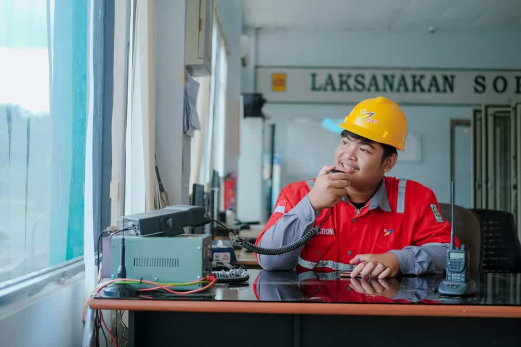 高雄外勞管理員在辦公室操作通訊設備，展現外籍勞工管理與溝通服務專業形象.