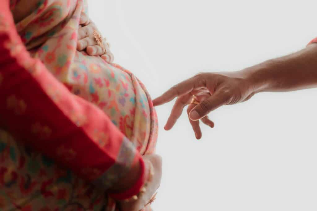 外勞幫助孕婦孕育生命的溫馨瞬間,亮眼的彩色孕婦衣與溫柔手指觸感,展現人道關懷與跨國合作。.